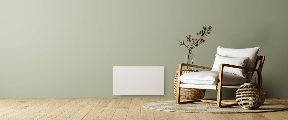 En stilren vit radiator monterad på en grön vägg i ett modernt vardagsrum. Elbutik.se erbjuder denna värmelösning som kombinerar effektivitet och design. Intill står en fåtölj och dekorativa föremål för en avslappnad atmosfär.