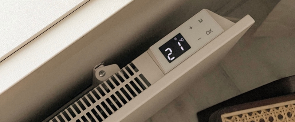 Närbild av en smart radiator från Elbutik.se med en digital termostat som visar 21°C. Panelen har knappar för temperaturkontroll, vilket gör den enkel att justera för optimal värme i hemmet.